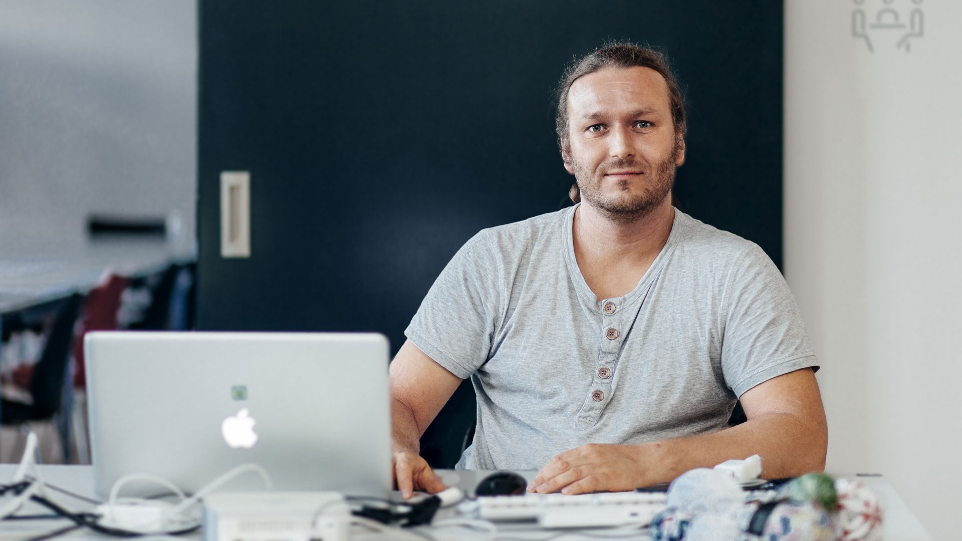 Björn sitzt im T-Shirt hinter seinem Laptop und allerlei weiteren Geräten.